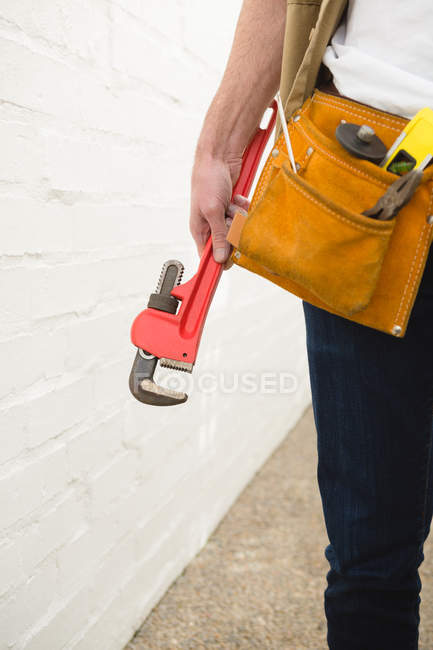Mid section of male carpenter with tool belt holding clamp — Stock Photo