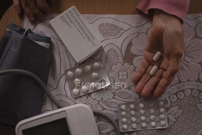 Primer plano de la mujer mayor sosteniendo píldora de medicina - foto de stock