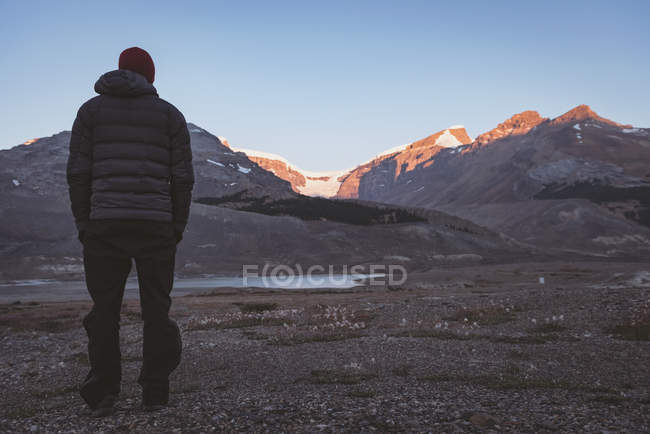 Rear view of man looking at snow capped mountains — Stock Photo