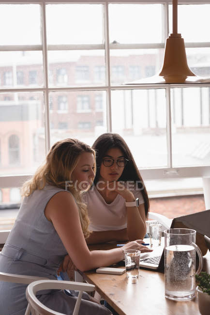 Женщины-руководители обсуждают за ноутбуком в офисе — стоковое фото