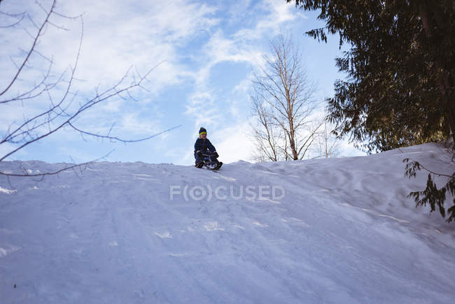 Lindo chico jugando en trineo durante el invierno - foto de stock