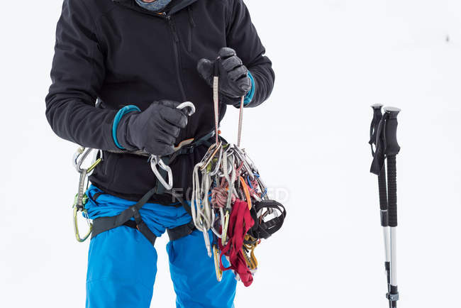 Male hiker holding carabiners on a snowy region during winter — Stock Photo
