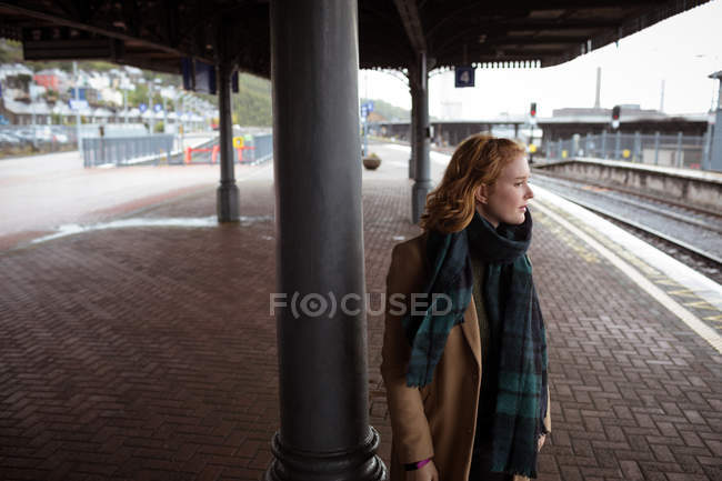 Mujer joven y curiosa esperando el tren en la plataforma del tren - foto de stock