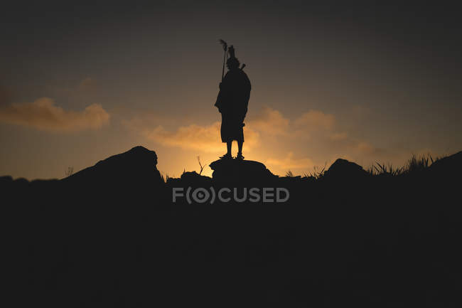 Silhouette dell'uomo maasai in piedi sulla roccia durante il crepuscolo — Foto stock