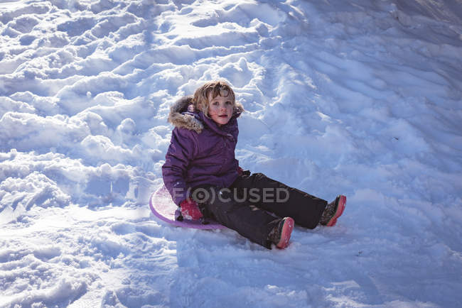 Retrato de menina bonito jogando no trenó durante o inverno — Fotografia de Stock