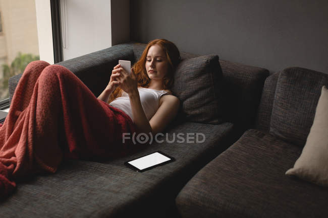 Young woman using mobile phone at home — Stock Photo