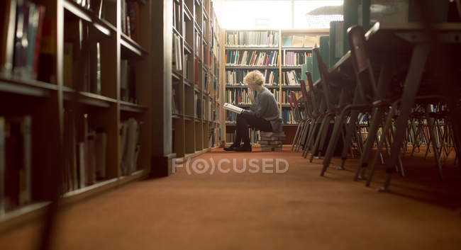 Молодая женщина, читающая книгу в библиотеке — стоковое фото