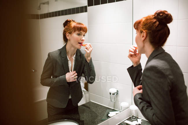 Деловая женщина наносит губную помаду в ванной комнате отеля — стоковое фото