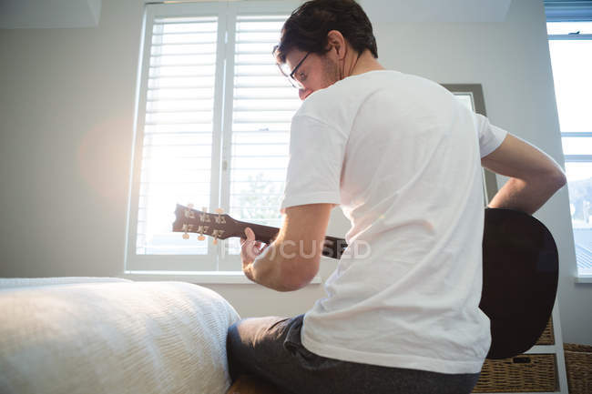 Homem tocando guitarra no quarto em casa — Fotografia de Stock