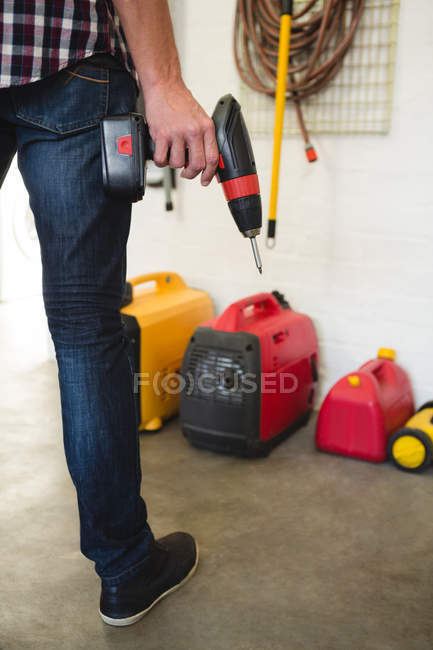 Low section of male carpenter holding drill machine in workshop — Stock Photo