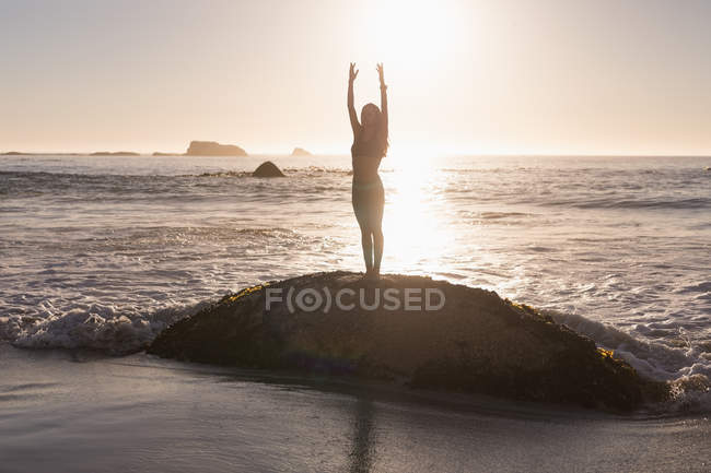 Вмістити жінку, що виконує йогу на пляжі в сутінках . — стокове фото