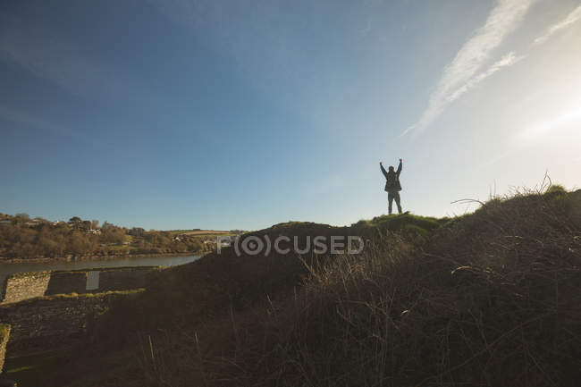 Rear view of male hiker standing with arms up at countryside — Stock Photo