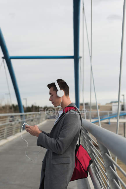 Чоловік слухає музику на навушниках на мосту — стокове фото