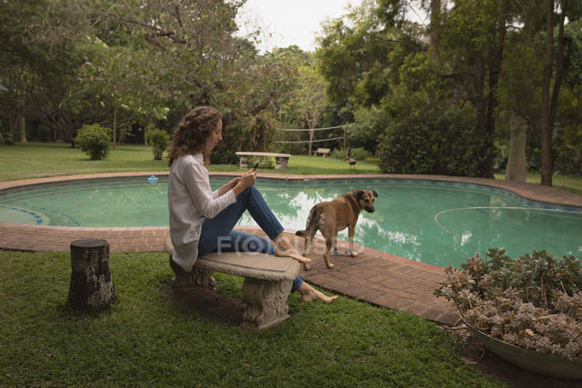 Woman and her pet dog relaxing near pool in the backyard — Stock Photo