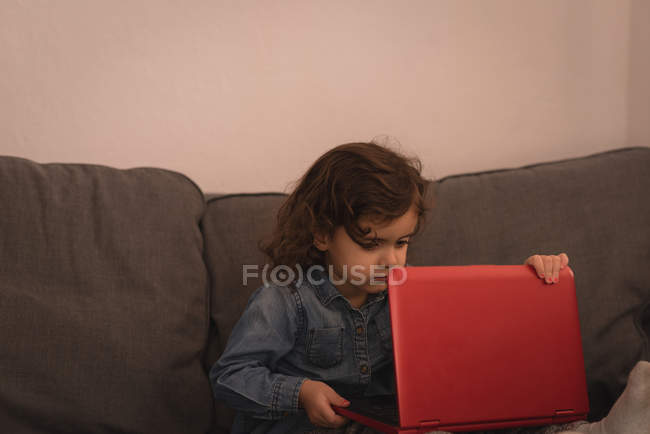 Kleines Mädchen benutzt Laptop im Wohnzimmer zu Hause. — Stockfoto
