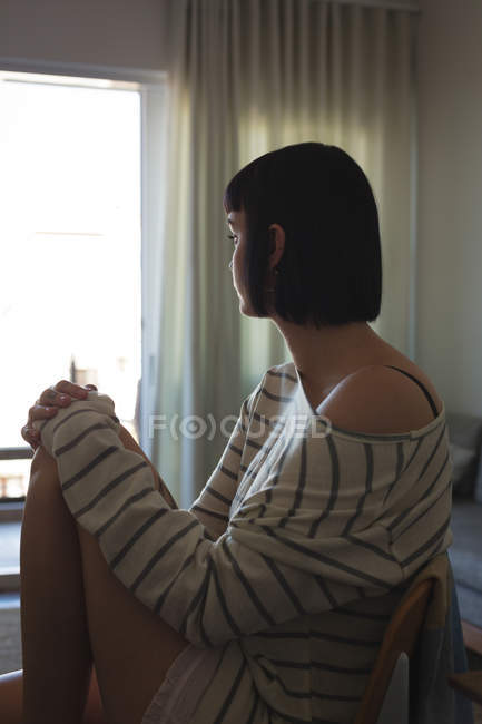 Worried woman sitting on sofa in living room at home — Stock Photo