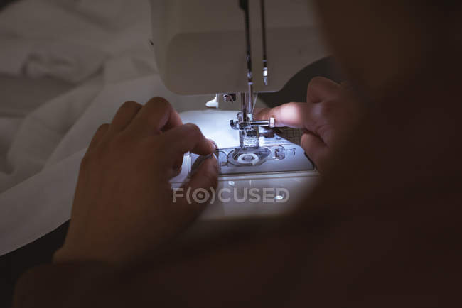 Primer plano de las manos de la mujer cosiendo paños en la máquina de coser - foto de stock