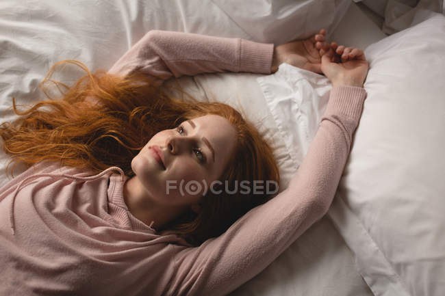 Nachdenkliche Frau entspannt sich auf dem Bett im Schlafzimmer zu Hause — Stockfoto
