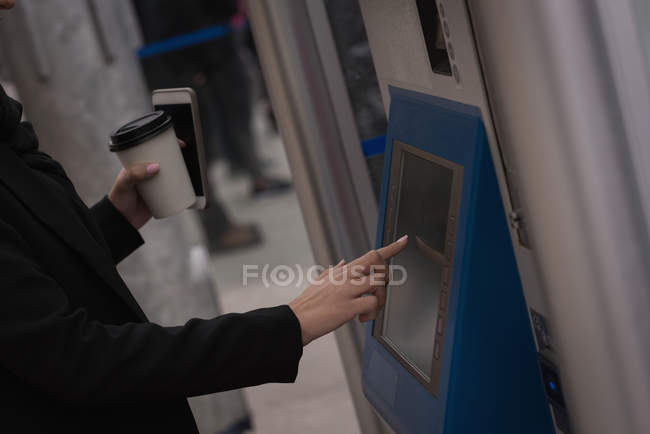 Средняя часть женщины пользуется билетным автоматом на вокзале — стоковое фото