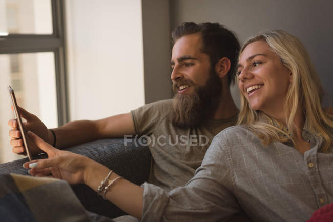 Пара, використовуючи цифровий планшет у вітальні вдома — стокове фото