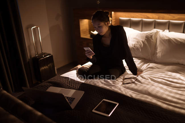 Жінка використовує мобільний на ліжку в готелі — стокове фото