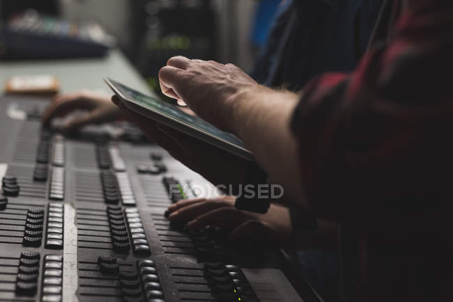 Two sound mixers using digital tablet in studio. — Stock Photo
