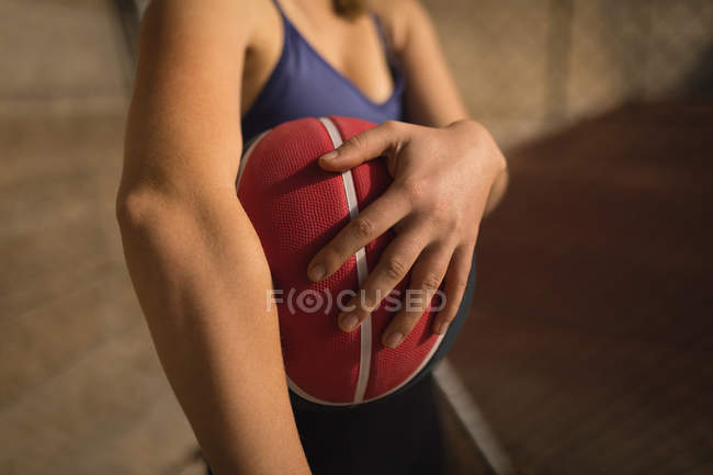 Partie médiane de la femme tenant le basket-ball dans le terrain de basket — Photo de stock