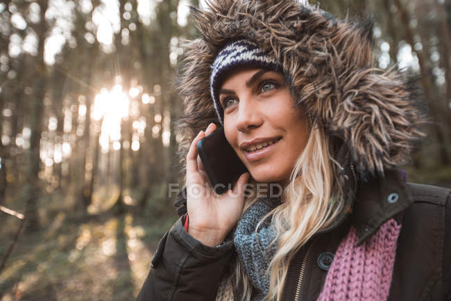 Mujer joven hablando por teléfono móvil en el bosque . - foto de stock