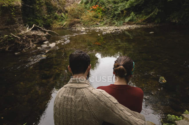Вид ззаду пари, що сидить на березі річки — стокове фото