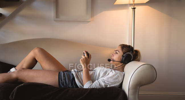 Frau spielt Videospiel mit Headset im heimischen Wohnzimmer — Stockfoto