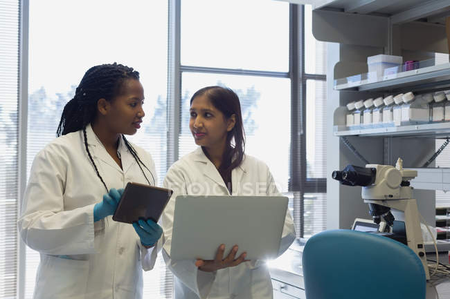 Dos científicas interactuando entre sí en el laboratorio - foto de stock