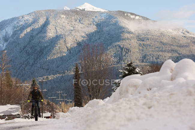 Uomo in bicicletta sulla strada innevata durante l'inverno . — Foto stock