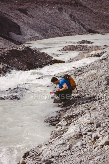 Männlicher Wanderer wäscht sich an einem sonnigen Tag im Fluss die Hände — Stockfoto