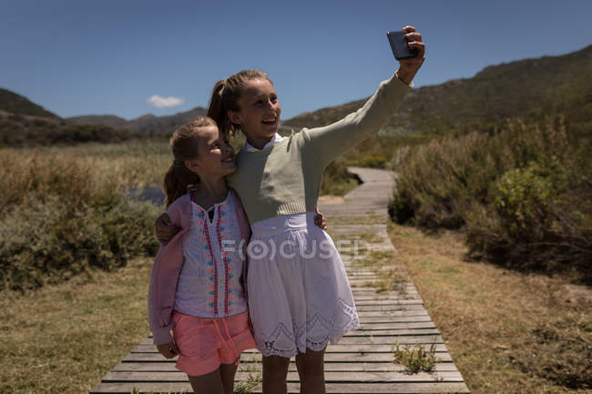 Irmãos felizes tirando selfie com celular no molhe — Fotografia de Stock