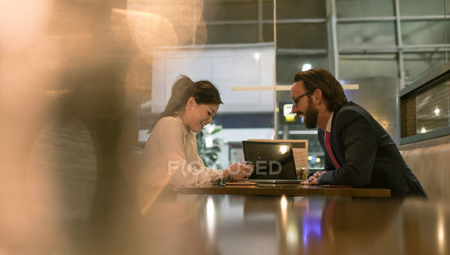 Businessman and woman interacting with each other in waiting area at airport — Stock Photo