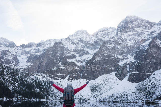 Vista posteriore della donna con zaino in piedi con le braccia tese durante l'inverno — Foto stock