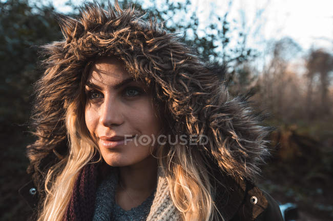 Young woman in hoodie standing at forest — Stock Photo