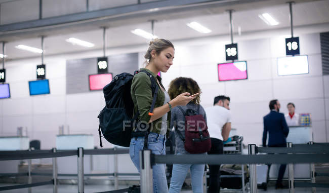 Жінка використовує мобільний телефон, стоячи в черзі в аеропорту — стокове фото
