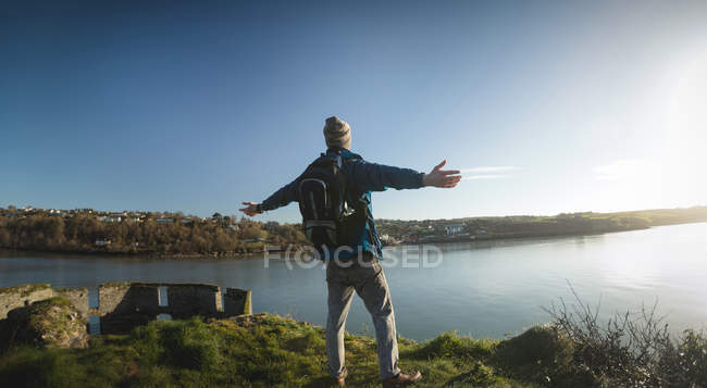 Vista posteriore dell'escursionista maschio in piedi con le braccia tese in campagna — Foto stock