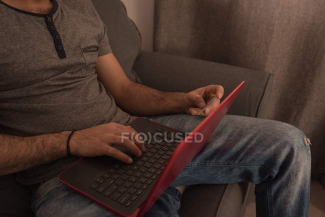 Mann benutzt Laptop auf Sofa im heimischen Wohnzimmer. — Stockfoto