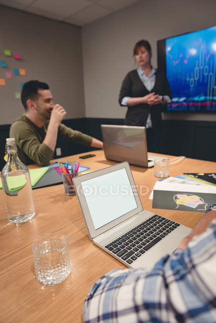 Businesswoman giving presentation to colleagues in meeting room at office — Stock Photo
