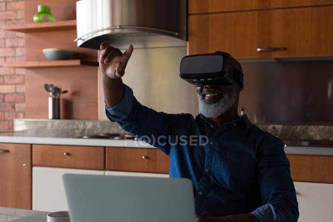 Uomo anziano sorridente utilizzando cuffie realtà virtuale a casa — Foto stock