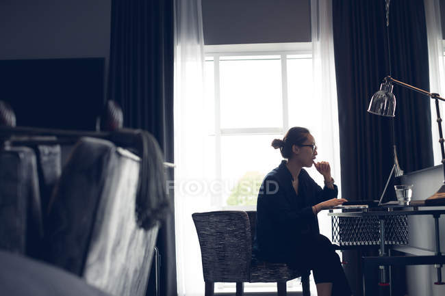 Mulher usando laptop à mesa no quarto de hotel — Fotografia de Stock
