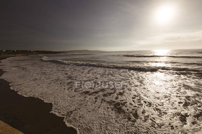 Belo pôr do sol sobre a onda do mar na praia arenosa . — Fotografia de Stock