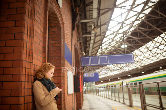 Junge Frau benutzt Handy am Bahnhof — Stockfoto