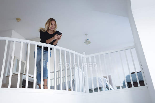 Junge Frau benutzt Handy zu Hause — Stockfoto