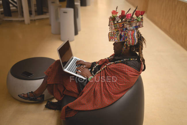 Uomo Maasai in abbigliamento tradizionale utilizzando il computer portatile al centro commerciale — Foto stock
