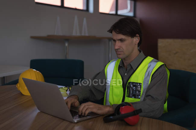 Trabajador masculino usando el ordenador portátil en el escritorio en la oficina - foto de stock