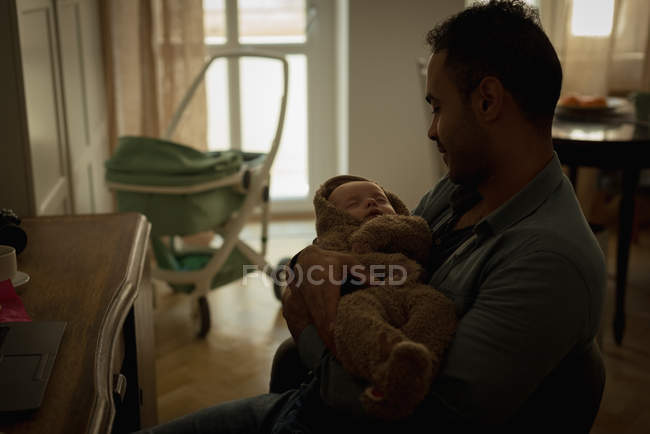 Pai segurando seu bebê na sala de estar em casa — Fotografia de Stock