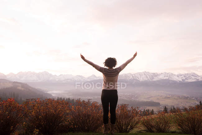 Rear view of woman standing with arms outstretched — Stock Photo